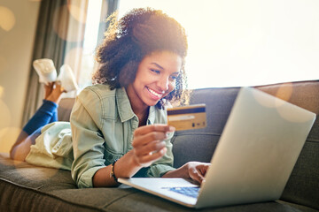 I have the power of the card in my hand. Shot of a cheerful young woman doing online shopping while...