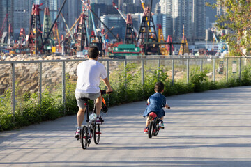 29 5 2021 father and son ride bicycles in West Kowloon Waterfront Promenade, Hong Kong. Back view....
