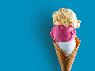 three multi-colored scoops of ice cream on a blue clean background, space for text
