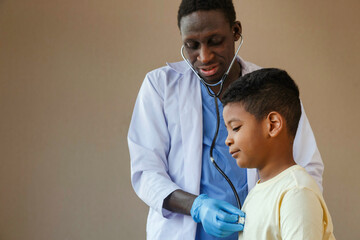 african american man pediatrician doctor using stethoscope to examining little boy from sickness in the office at the hospital. medical and healthy lifestyle concept.