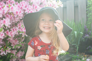 Fototapeta premium Smiling cute caucasian blonde toddler girl in a hat enjoying summer sunny day outdoors