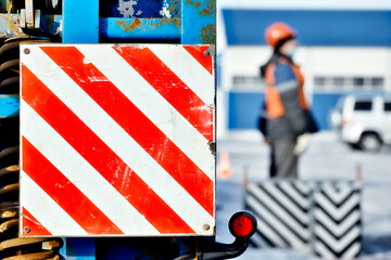 Sign is careful on trawling technique. Red white stripes on flat surface. Lifting cargo on street....