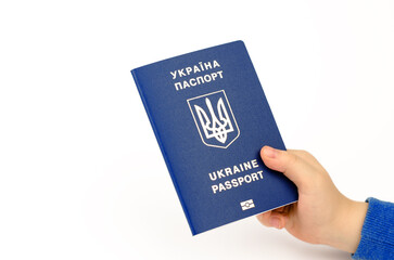 Biometric passport of a citizen of Ukraine in a child's hand on a white background. The inscription on the Ukrainian passport of Ukraine.