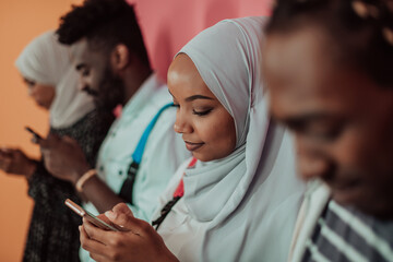 A group of African Muslim students use smartphones while standing in front of a yellow background