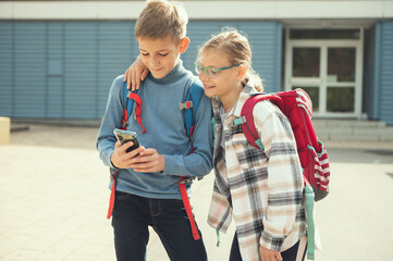 Teen schoolchildren playing with cell phone in school yard