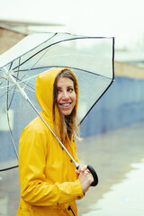 Cropped side portrait of caucasian woman in yellow clothes under rain with umbrella outdoors. Vertical view of caucasian happy woman isolated smiling with dental braces. Rain lifestyle concept