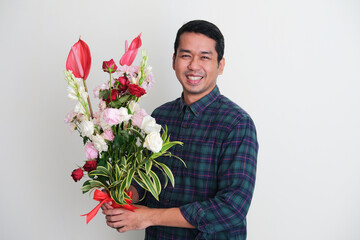 Adult Asian man smiling happy when holding flowers arrangement