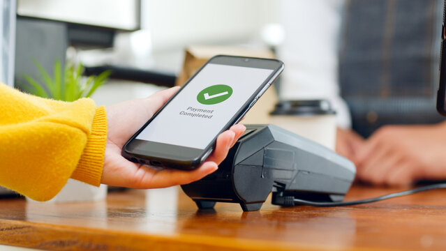 Customer using smartphone for NFC payment at cafe restaurant, cashless, contactless technology and money transfer concept