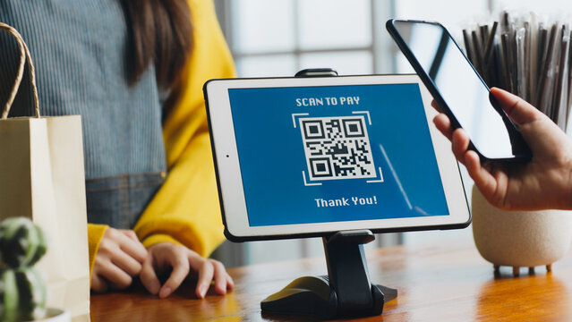 Customer using phone for payment at cafe restaurant, cashless QR code technology and money transfer concept
