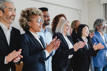 Multiracial and multi-generational group of people celebrating together inside bank office - Soft focus on Chinese woman clapping hands - obrazy, fototapety, plakaty