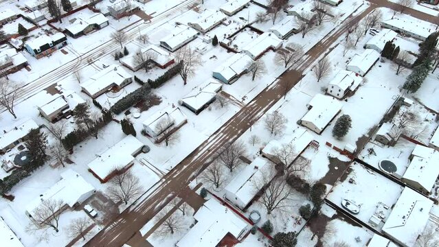 Snow covered neighborhood of mostly one story ranch houses, aerial view.
