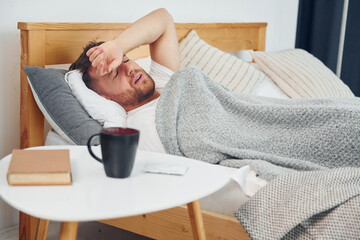 Sick man laying down on the bed at home and feels bad. Conception of self isolation © standret