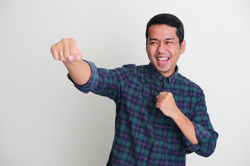 Fototapeta premium Adult Asian man punching forward with excited face expression