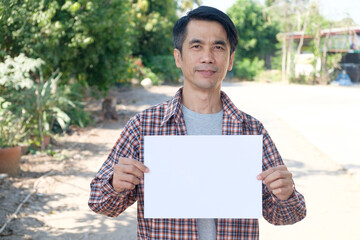 Smiling Asian farmer holding a white sign at the farm