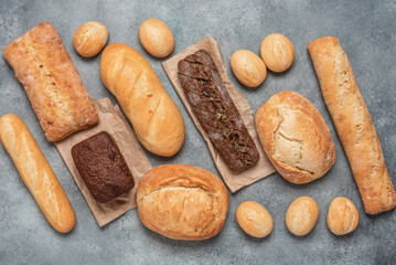 Homemade fresh bread. Gray concrete background. Collection of various bakery products. Top view, flat lay.