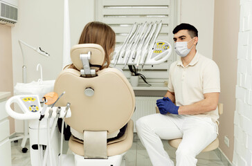 Dental practitioner wearing face protection while folding arms on his chest near his patient