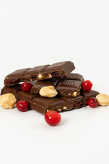 Stack of milk and dark chocolate with nuts, caramel and fruits and berries on a white background.