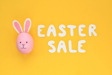 Colourful eggs with funny bunny and lettering Easter sale on yellow background. Easter sale banner with easter decorated eggs. Top view, flatlay creative concept for postcard, poster, magazine