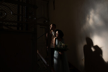 Silhouette of a bride and groom in the dark room with shadows.