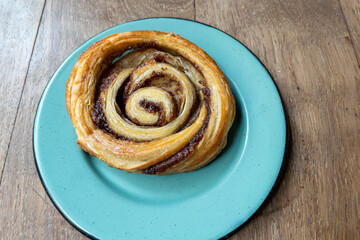 top view of a cinnamon roll bread on a blue plate on a wooden table