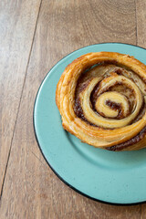 top view of a cinnamon roll bread on a blue plate on a wooden table