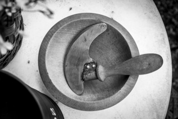 Top greyscale view of a wooden bowl and a cutter with handle