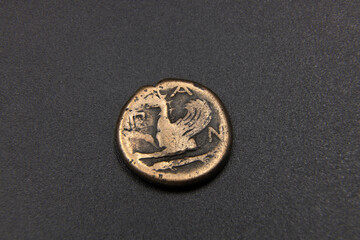 Antique copper Greek coin on black background