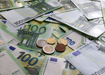 Obraz premium Euro cent coins on the background of 100 Euro banknotes arranged in random order