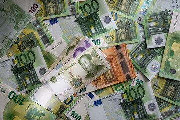 1 Chinese yuan banknote on the background of 100 Euro banknotes arranged in random order