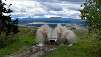 Car driving on a puddle splashing mud