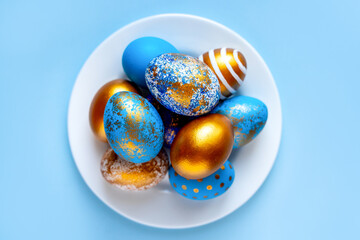 easter eggs blue gold color beautiful painted for holy easter lie on a plate on a blue background