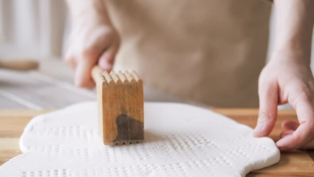 Handcraft woman master modeling cold porcelain, hands makes pattern and texture on the dough, beats it with wooden mallet, hobby for the soul scandinavian and boho style interior decor