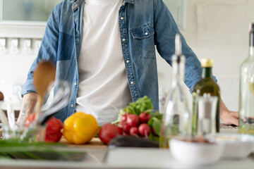 Close up of man leaning on kitchen counter with vegetables. Portrait of casual guy in the kitchen with ingredients on it