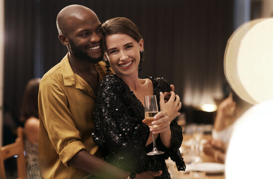 I Found Love This Year. Shot Of A Happy Young Couple Standing Close Together During A New Years Eve Dinner Party.