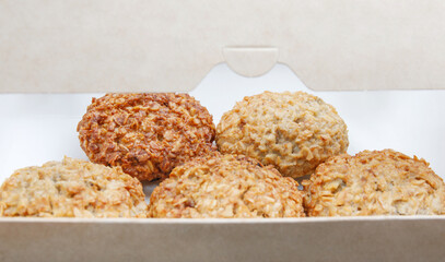 Crunchy homemade oatmeal cookies lie in an ajar cardboard box.