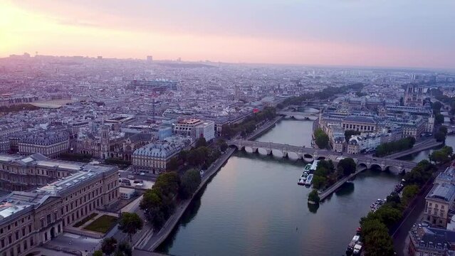 Flying over Seine river towards Ile de la Cite at sunrise. Panning view on Paris panorama. Pont Neuf bridge and Vedettes du Pont Neuf in foreground.