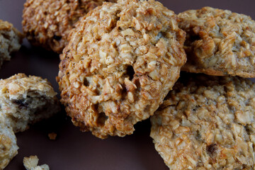 Whole and crushed handmade oatmeal cookies on a brown background. View from above .