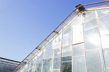 Obraz premium Old destroyed greenhouse with broken window glasses and rusty frame. Urban ruined geometry. Blue sky.