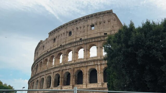 Slow panning shot of old historic Colosseum Amphitheatre in Rome against clouds at sky,Italy