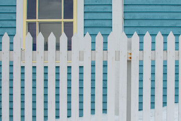 Two double hung windows on a blue exterior wall of a vintage style building. The building has...