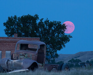 Scenic view of the pink full moon over the field with a chevy truck in Owanka, South Dakota