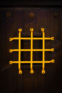 Vertical Shot Of A Yellow Iron Speakeasy Grille On A Wooden Door