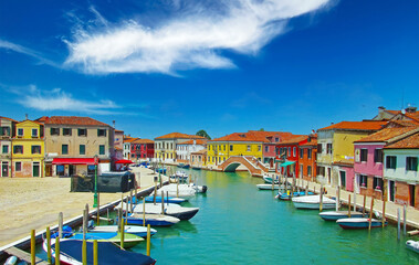 Obraz premium Venice (Murano), Italy - Picturesque calm typical italian town, water canal with boats, bridge, bright colorful houses against clear blue sky, fluffy cloud