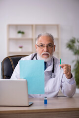 Fototapeta premium Old male doctor working in the clinic
