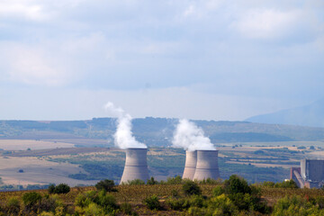 smoking chimneys of a thermal power plant against the backdrop of a mountainous landscape in...