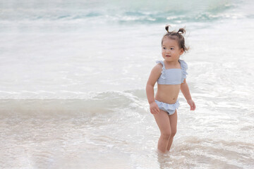 Cute Baby Girl in Bikini Walking on the Beach for Summer Vacation