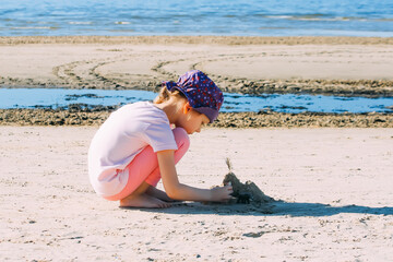 Little girl playing with sand on the sea coast. 