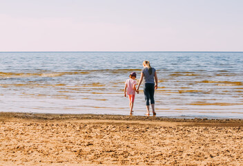 Two girl walks on a sandy beach. Children on the sea coast. 