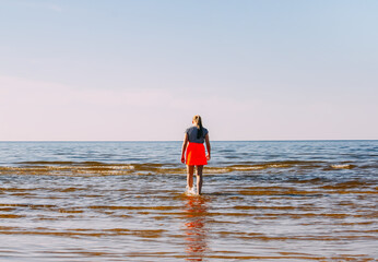 Teenager girl walks on the Baltic sea coast in a warm spring day. 