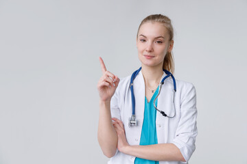 Young european woman wearing doctor with stethoscope pointing with finger up, gesture paying...